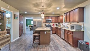 A spacious kitchen with wooden cabinets, a central island, and a microwave.