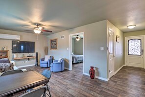 Un salon spacieux comprenant un coin repas, un ventilateur de plafond, un téléviseur à écran plat et une porte ornée de vitraux.