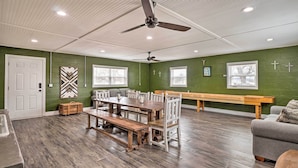 A dining area with a wooden table and benches, green walls, and ceiling fans.