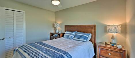 A bedroom with a bed, two nightstands, a ceiling fan, and a door.