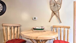 A wooden table with two chairs, each with a red cushion. A small white device is mounted on the wall above the table. - Biwabik Vacation Rental Near Giants Ridge! (Aurora)