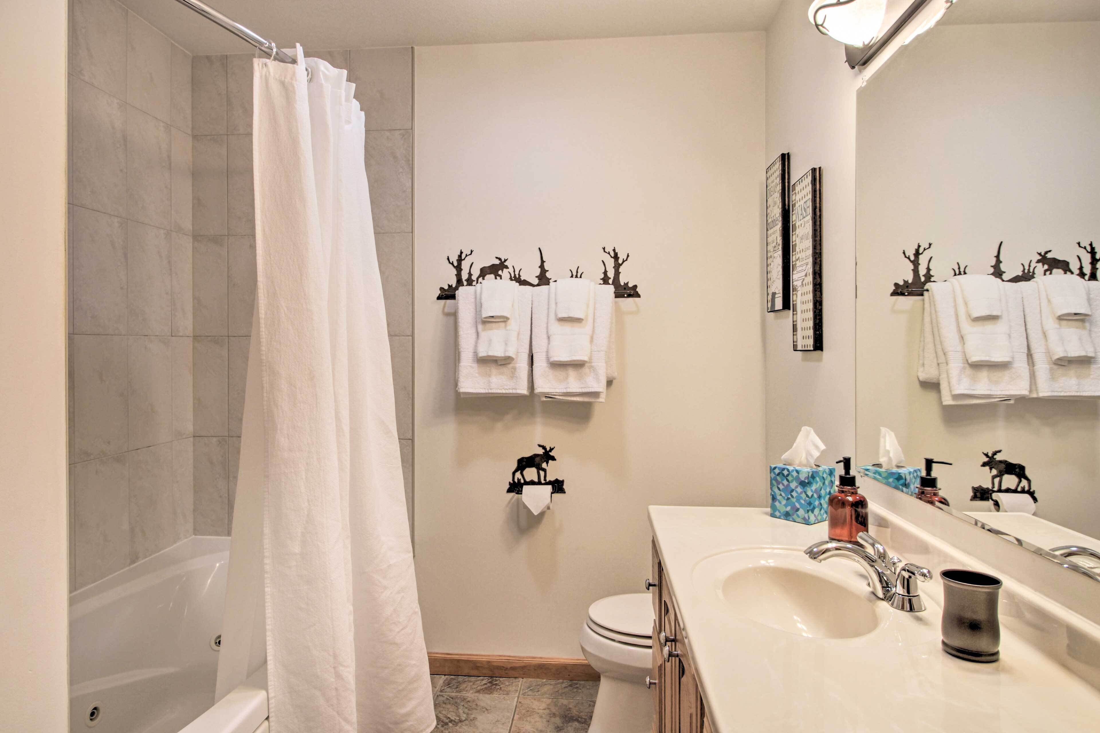 A bathroom with a bathtub, toilet, and sink. There are towels hanging on a rack and a mirror above the sink.