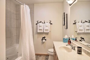 A bathroom with a bathtub, toilet, and sink. There are towels hanging on a rack and a mirror above the sink.
