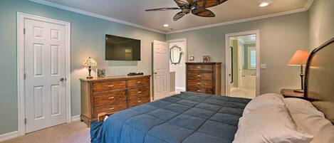 A bedroom with a bed, dresser, and ceiling fan.