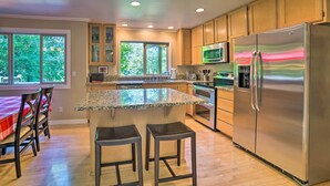 Une cuisine moderne dotée de plans de travail en granit, d’appareils électroménagers en acier inoxydable et d’armoires en bois.