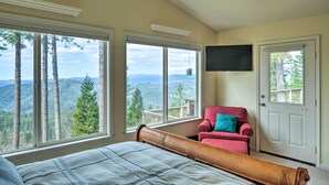A bedroom with a large bed, a red armchair, and a TV mounted on the wall. - Near Hiking: Home w/ Deck in Twain Harte! (Mi-Wuk Village)
