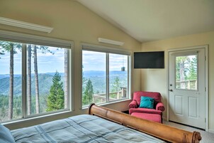 Un dormitorio con una cama grande, un sillón rojo y un televisor montado en la pared.