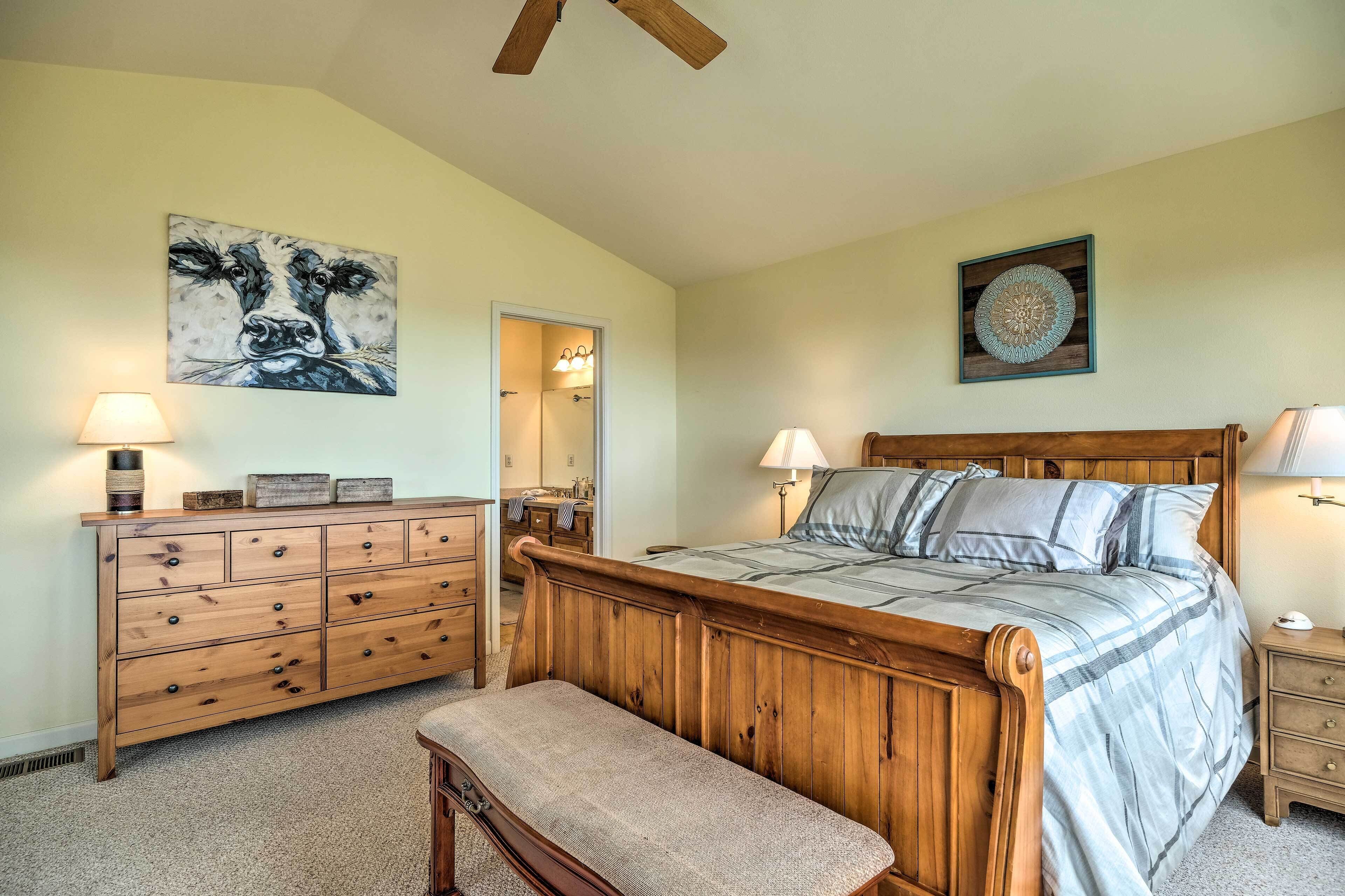 A bedroom with a wooden bed, a bench, a dresser, and a mirror.