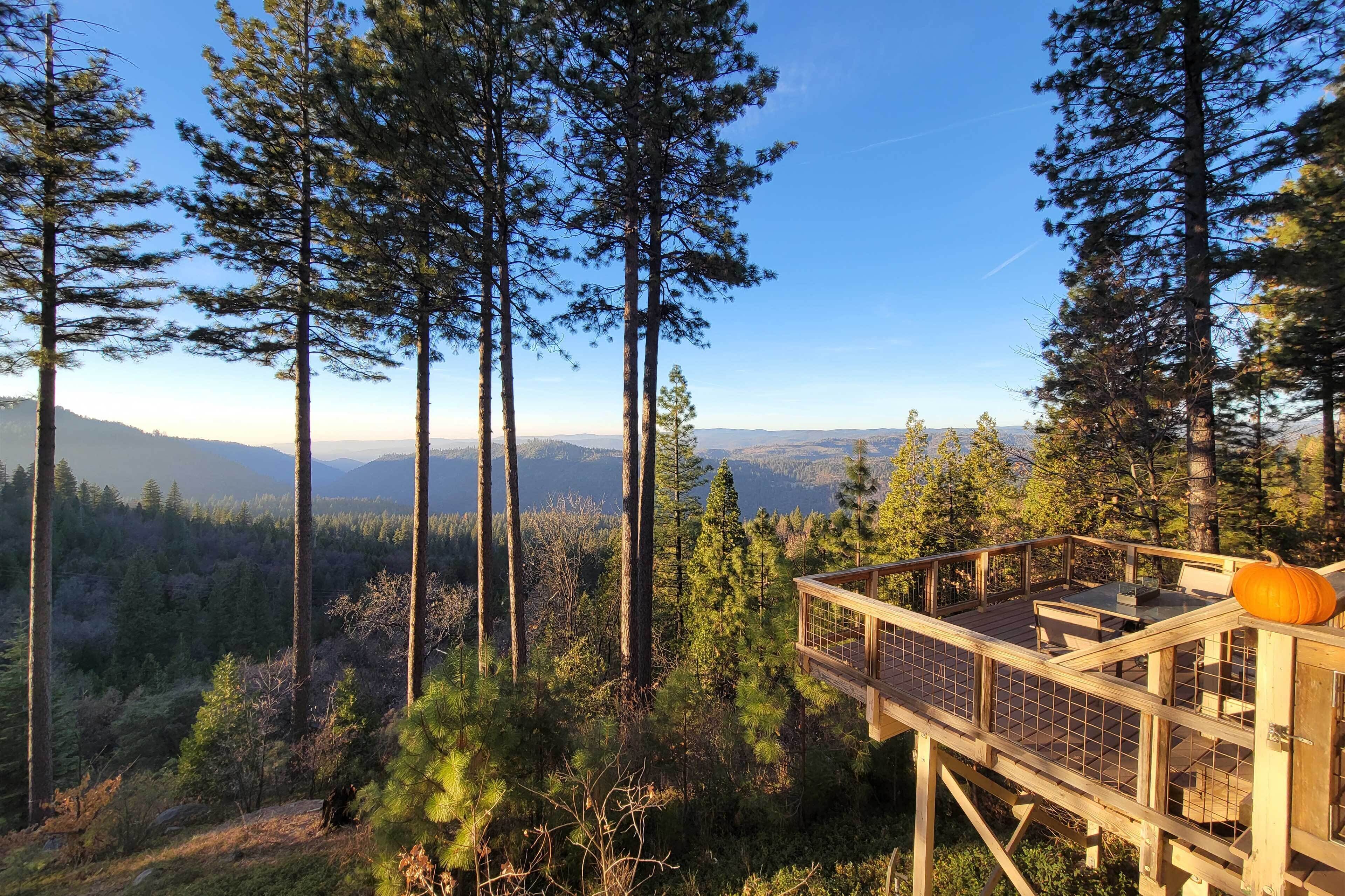 A wooden deck with a view of a forest and mountains.