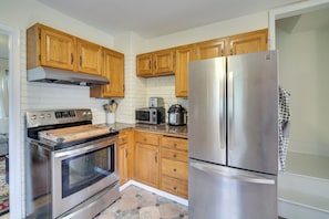 A kitchen with wooden cabinets, a stainless steel refrigerator, a microwave, and an oven. - Charming Tacoma Vacation Home w/ Fenced Yard (Tacoma)