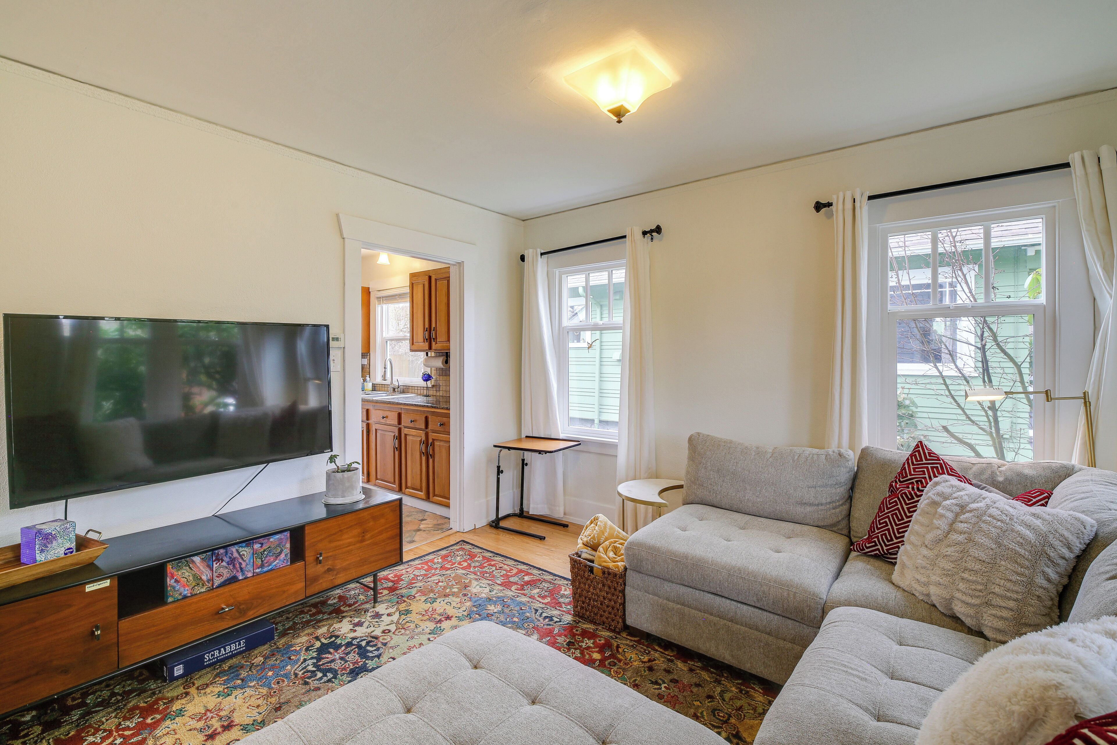 A living room with a flat-screen TV, a sofa, a coffee table, and a patterned rug.