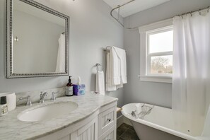 A bathroom with a marble sink, a large mirror, a bathtub, and a window with a curtain. - Charming Tacoma Vacation Home w/ Fenced Yard (Tacoma)
