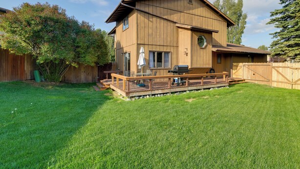 A two-story wooden house with a deck, a barbecue area, and a fenced backyard. - Charming Anchorage Home w/ Grill + Deck! (Anchorage)