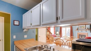 A kitchen with white cabinets, a wooden countertop, a double sink, and a microwave. - Charming Anchorage Home w/ Grill + Deck! (Anchorage)