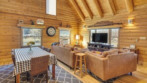 A cozy log cabin interior with a dining area, sofa, and TV. - Cottonwood Cabin w/ Private On-site Fly Fishing! (Blanco)