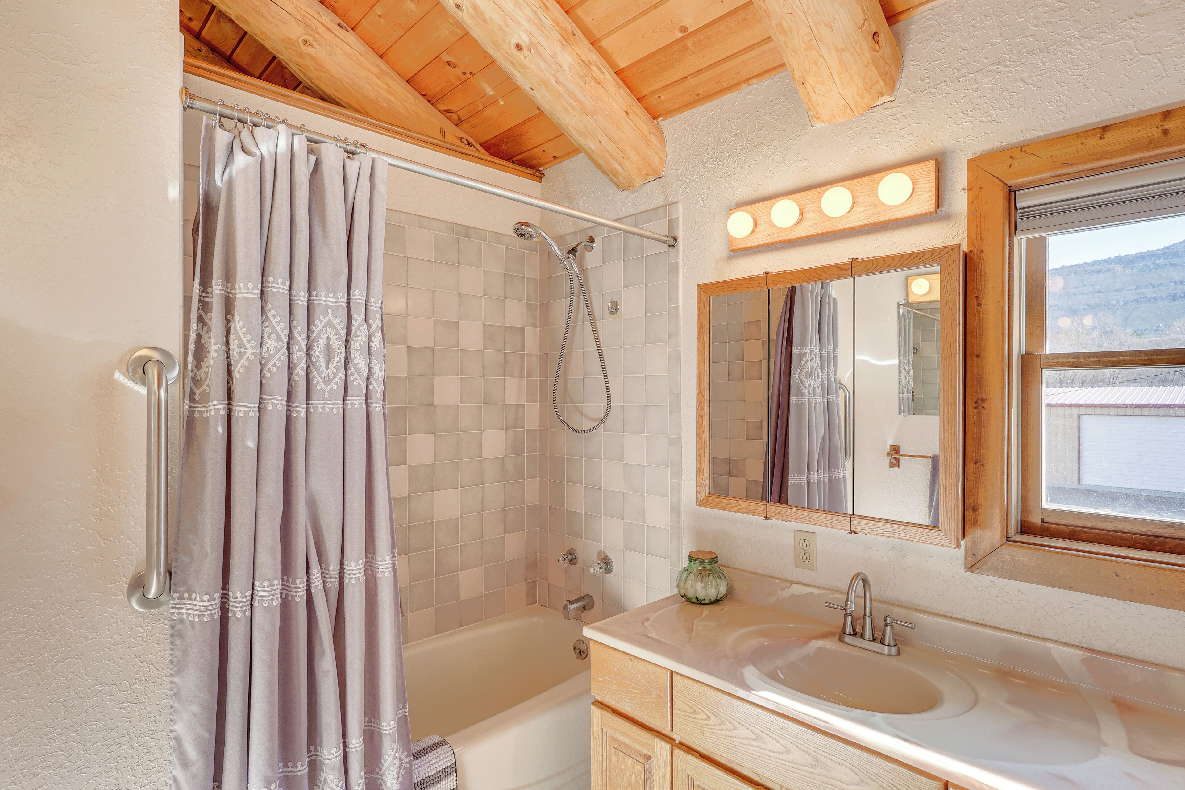 A bathroom with a shower, a sink, and a mirror.