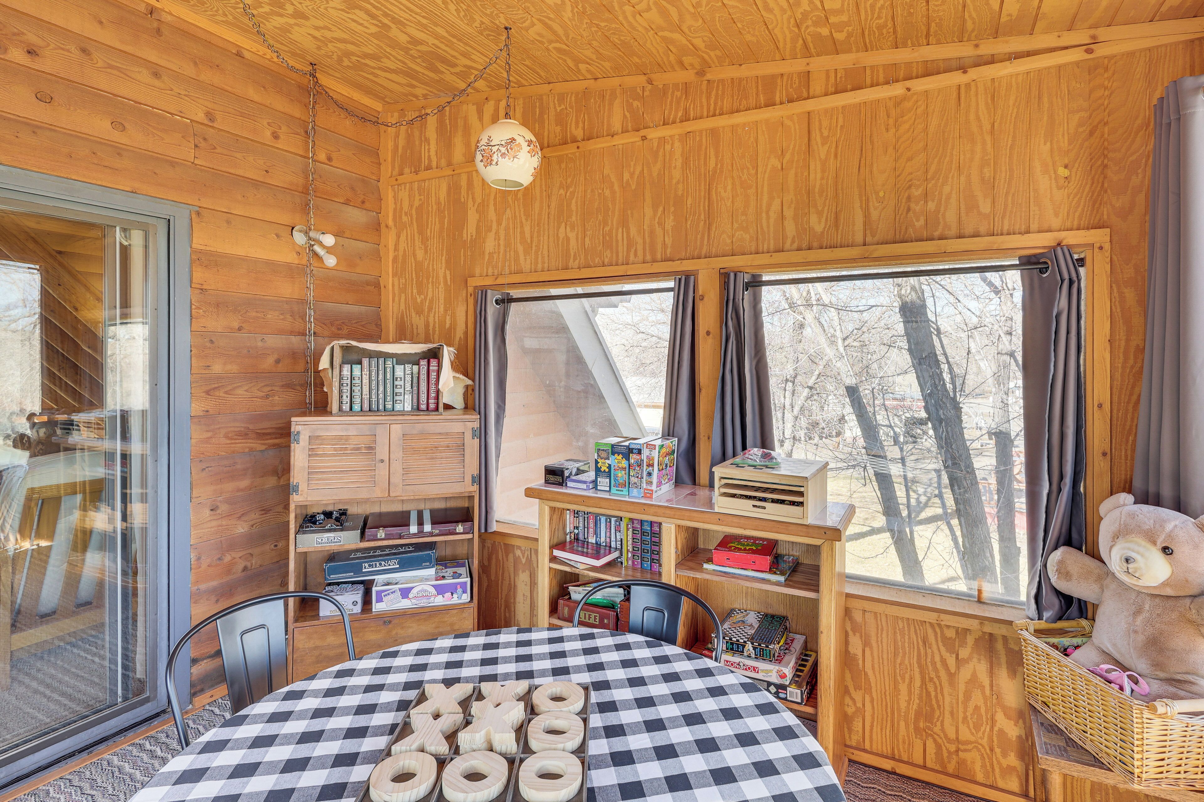 A cozy cabin with wooden walls, a checkered table, and a large window with curtains.