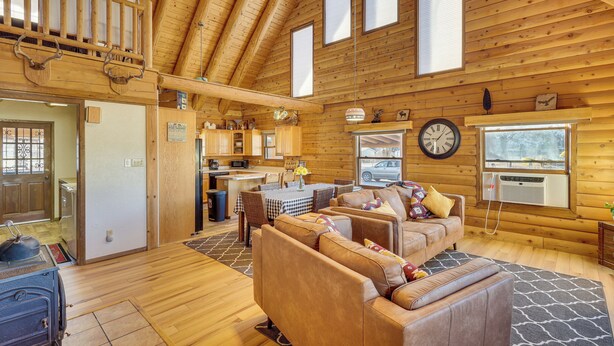 A cozy log cabin interior with a dining area, kitchen, and a living room with leather sofas. - Cottonwood Cabin w/ Private On-site Fly Fishing! (Blanco)