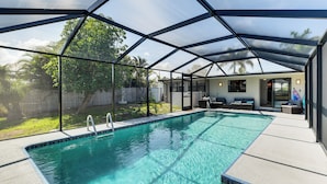 A swimming pool with a glass enclosure, surrounded by a patio area with seating and a view of the backyard. - 8 Mi to Charlotte Sports Park: Home w/ Gulf Access (Port Charlotte)