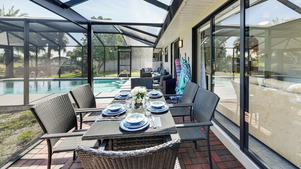 A covered patio with a table set for dining, overlooking a swimming pool. - 8 Mi to Charlotte Sports Park: Home w/ Gulf Access (Port Charlotte)