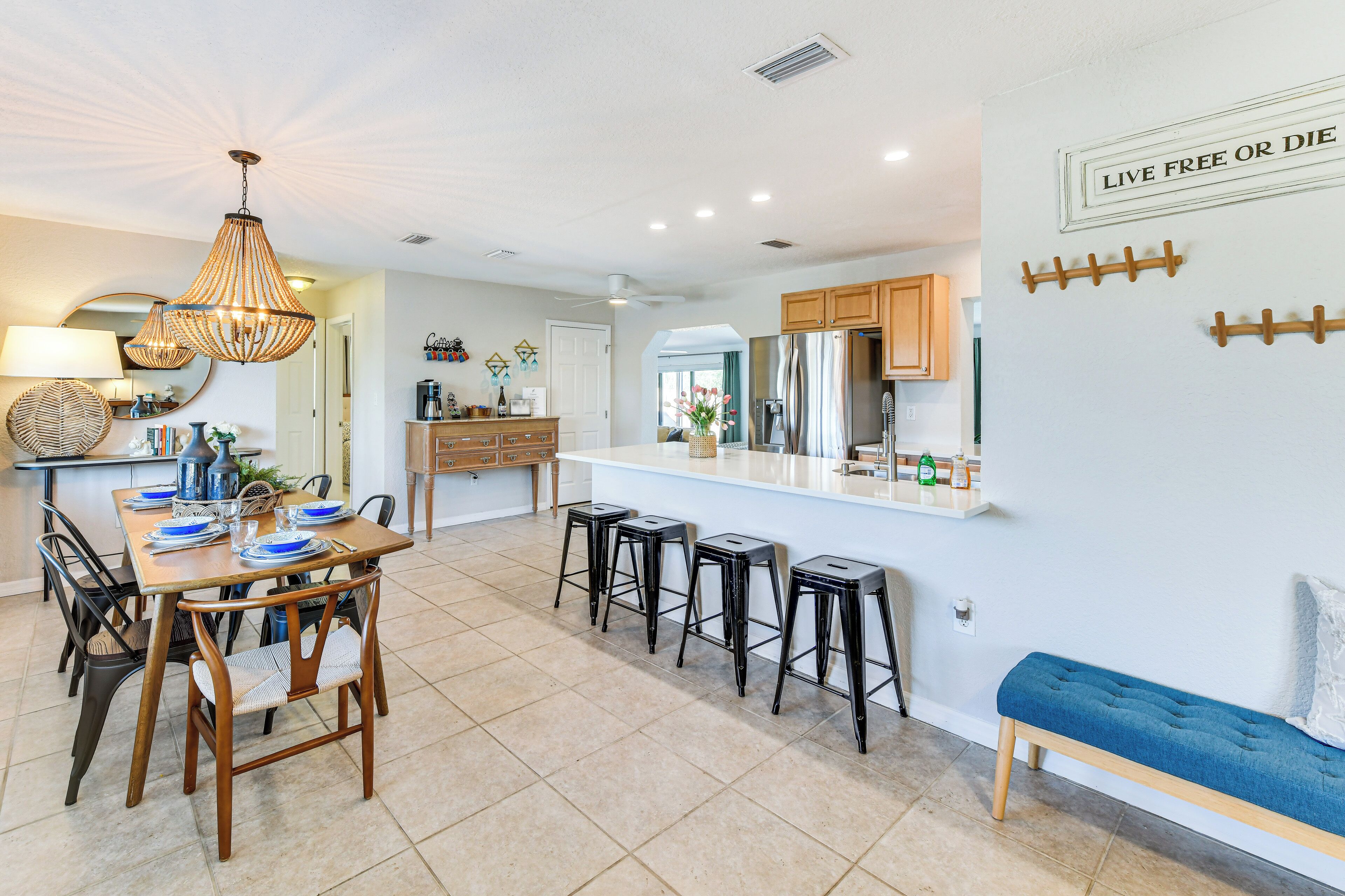 A modern kitchen with a dining area, featuring a wooden table, bar stools, and a bench.
