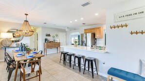 A modern kitchen with a dining area, featuring a wooden table, bar stools, and a bench. - 8 Mi to Charlotte Sports Park: Home w/ Gulf Access (Port Charlotte)