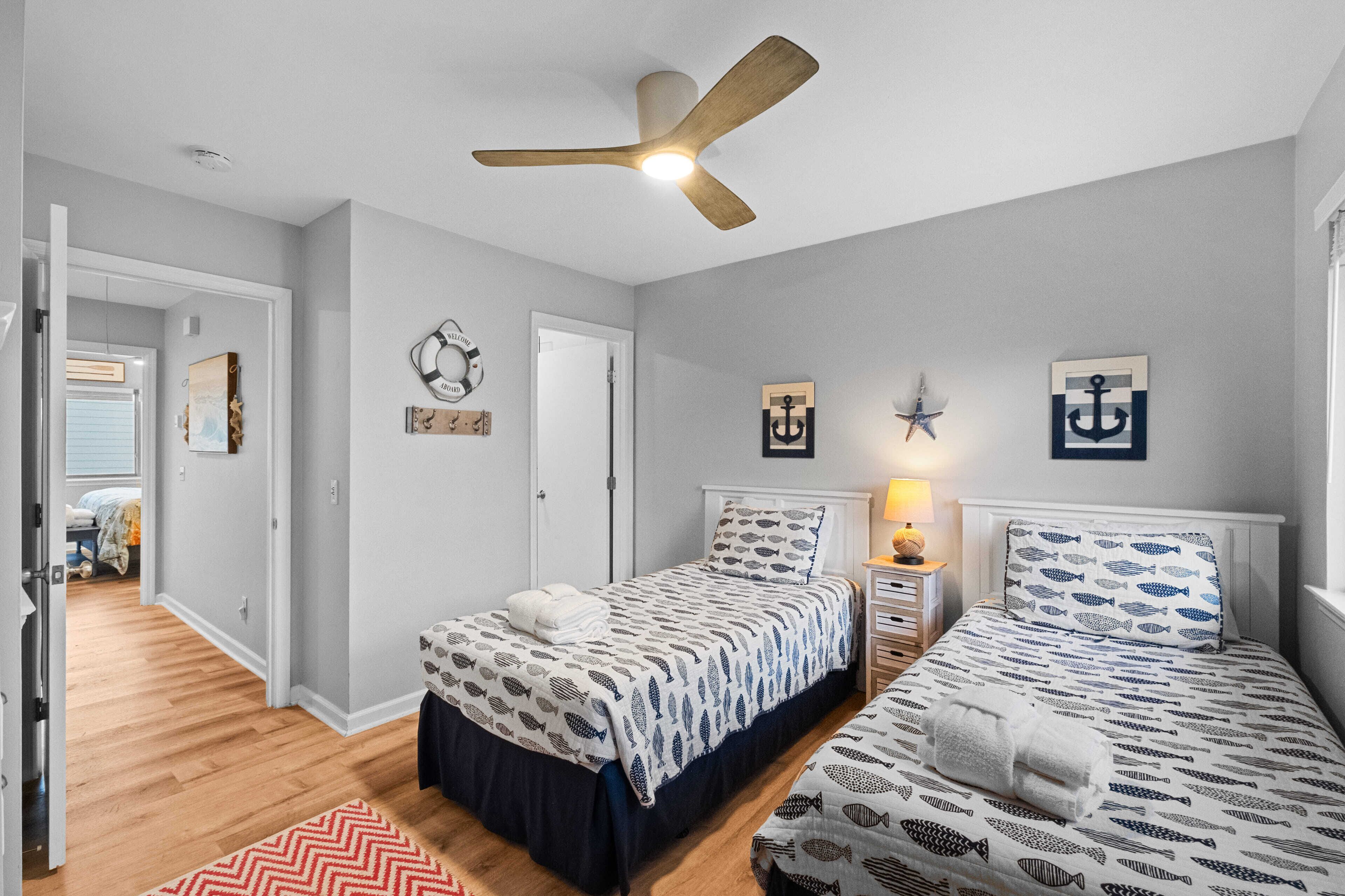Un dormitorio con dos camas, ventilador de techo y decoración náutica.