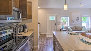 A modern kitchen with stainless steel appliances, a wooden countertop, and a dining area with a table set for two. - Riverfront Sheboygan Townhome w/ Grill! (Sheboygan)