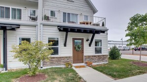 A two-story house with a front porch, stone foundation, and a small tree. - Riverfront Sheboygan Townhome w/ Grill! (Sheboygan)