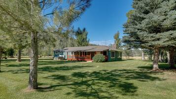 A house with a porch, surrounded by trees and a well-maintained lawn.