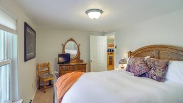 A bedroom with a bed, a dresser, a chair, a television, and a mirror.