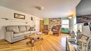 Una sala de estar con un sofá, dos sillones, una mesita de centro, una chimenea y un televisor.