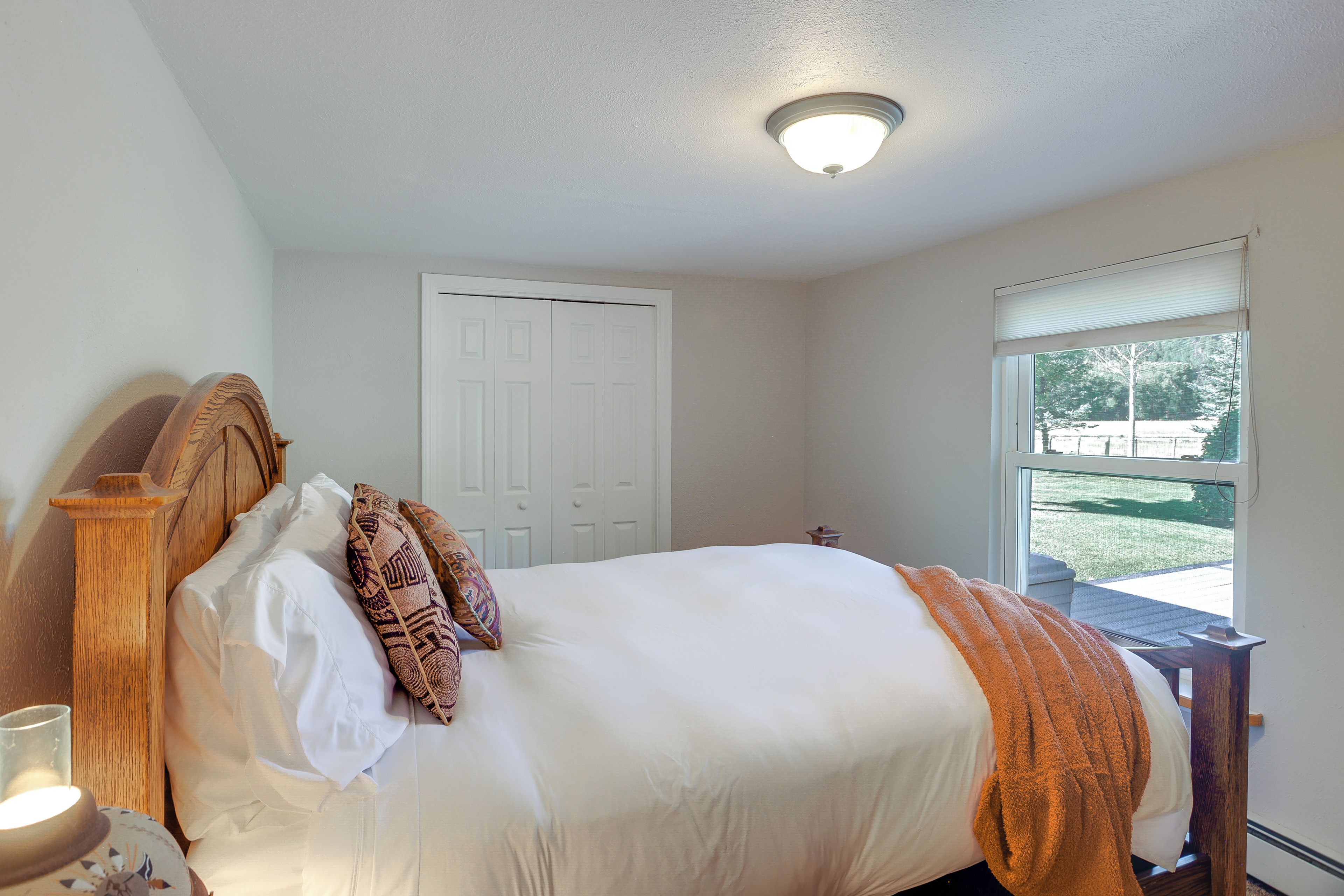 A bedroom with a bed, a nightstand, a window, and a door.