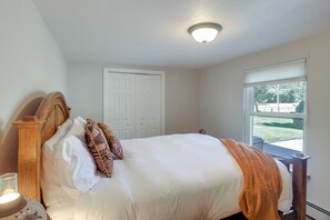 Una camera da letto con un letto, un comodino, una finestra e una porta.