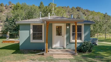 A small, single-story house with a front porch, a chimney, and a satellite dish.