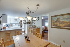 A dining area with a wooden table, chairs, a chandelier, and a painting on the wall.
