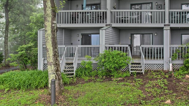 A multi-story residential building with balconies, a covered outdoor seating area, and a garden with various plants. - Ski-in Ski-out Condo w/ Balcony & Slope Views! (Nellysford)