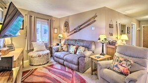 A cozy living room with a sofa, armchair, ottoman, and a flat-screen TV. - Ski-in Ski-out Condo w/ Balcony & Slope Views! (Nellysford)