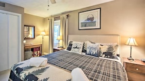 A bedroom with a bed, a ceiling fan, a bedside table with a lamp, a nightstand, a dresser, a mirror, and a framed picture on the wall. - Ski-in Ski-out Condo w/ Balcony & Slope Views! (Nellysford)