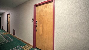 A hotel hallway with a wooden door, carpeted floor, and a wall-mounted intercom. - Ski-in Ski-out Condo w/ Balcony & Slope Views! (Nellysford)