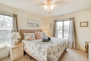 Um quarto com cama, mesa de cabeceira, luminária e ventilador de teto.