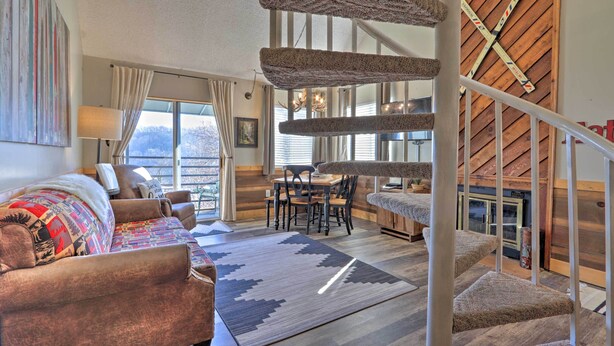 Ein gemütliches Wohnzimmer mit Sofa, Teppich, Essbereich und einer Treppe.