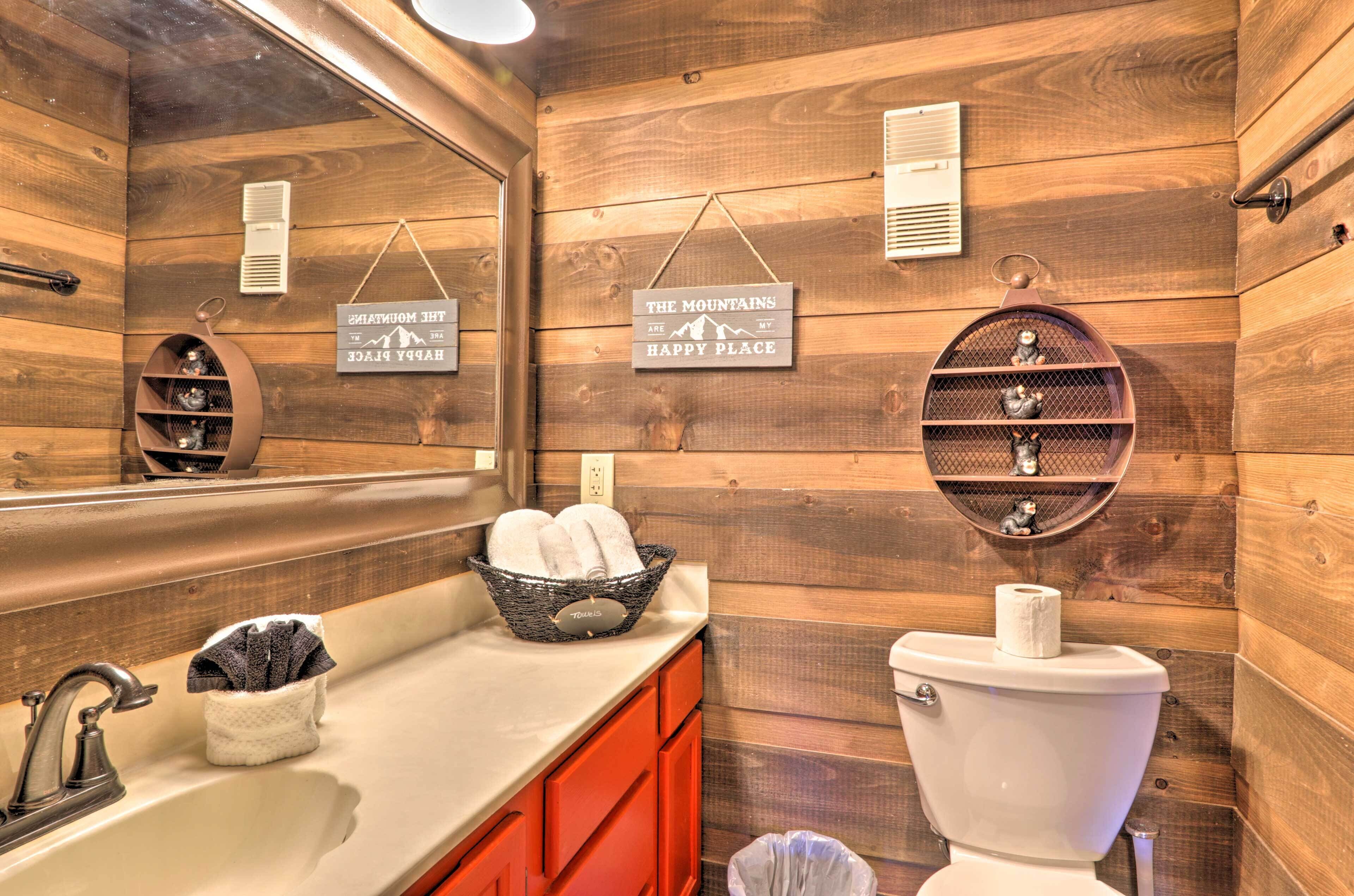 Baño de cabaña de madera con lavamanos, inodoro y perchero para toallas.