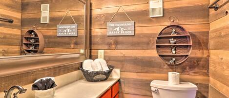 Baño de cabaña de madera con lavamanos, inodoro y perchero para toallas.