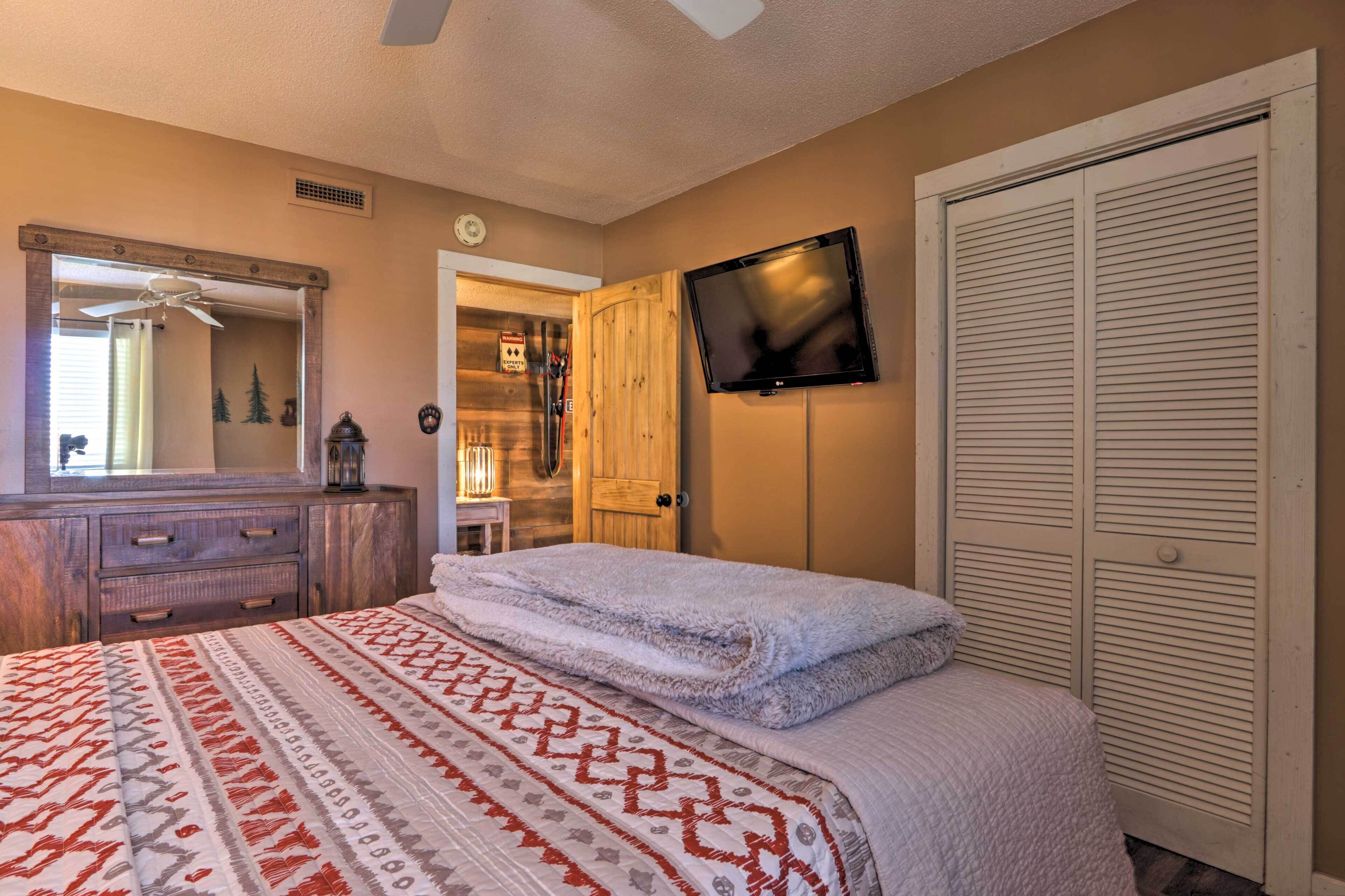 A bedroom with a bed, a dresser, a television, and a closet.