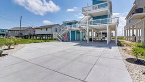 Una propiedad frente a la playa con un patio amplio, un edificio de varios niveles con balcón y vista despejada al océano.
