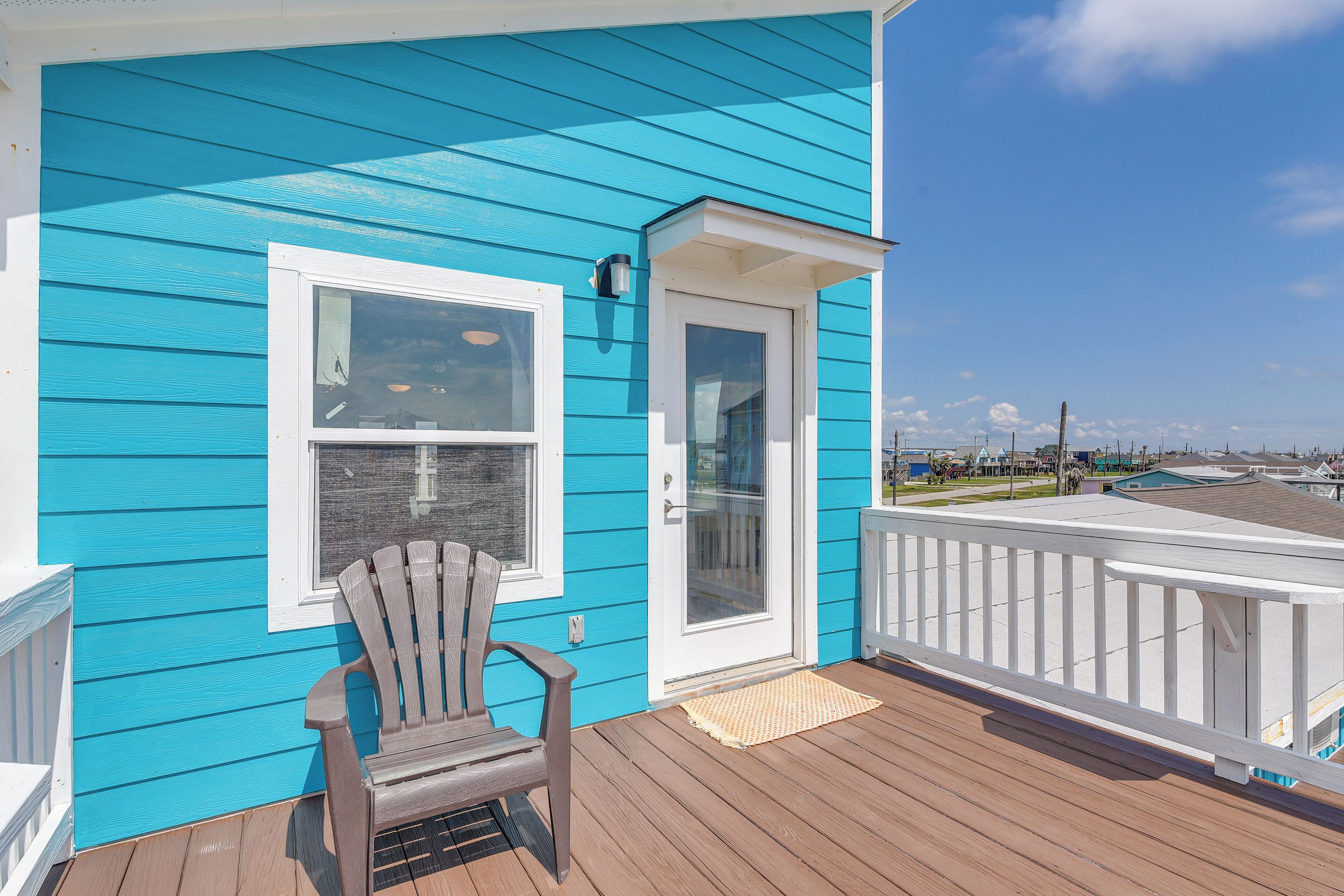 A wooden deck with a blue house, a door, and a window.