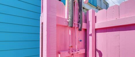 A pink wooden gate with a metal latch and a hose attached to it.