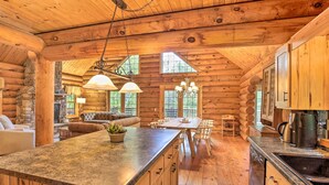L’intérieur d’une cabane en rondins, avec une cheminée en pierre, une table à manger en bois et un coin cuisine.