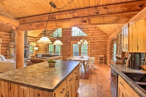 Ein Blockhaus-Interieur mit Kamin aus Stein, einem Holzespeisesaal und einer Küchenzeile.